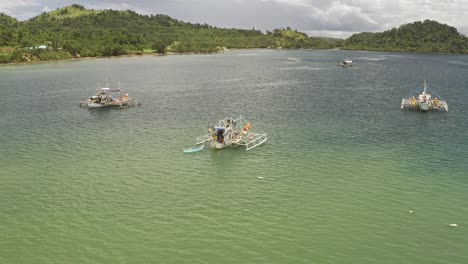 fishing trawlers off the coastal lush hillside landscape in the philippines with turquoise waters near surigao