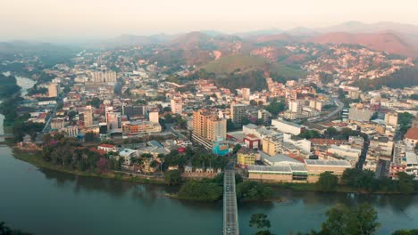 Aerial-Pan-View-of-Downtown-Barra-do-Piraí,-Rio-de-Janeiro,-Brazil-over-the-Paraíba-do-Sul-River-at-Dusk