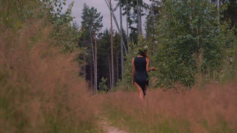 joven mujer caucásica con un vestido azul con una corona en la cabeza caminando por el bosque durante la primavera