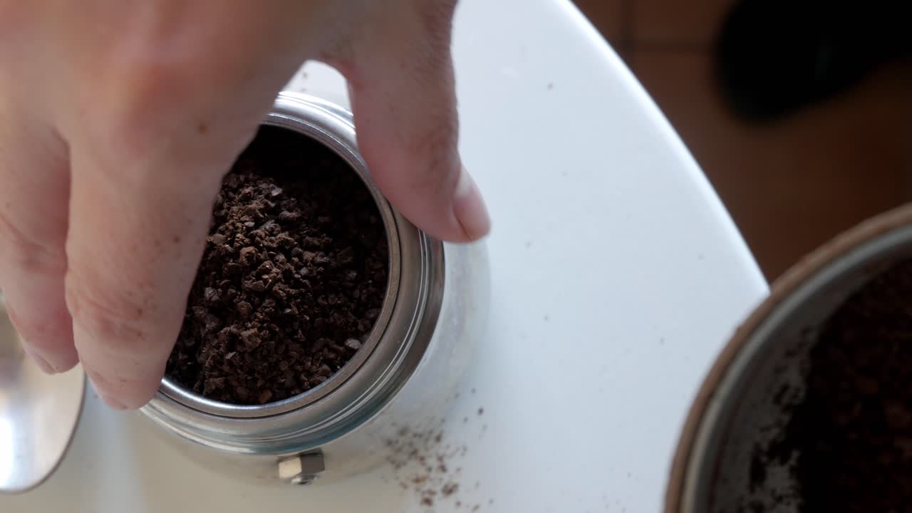 Grinding fresh coffee beans in a container, close-up shot showing ground coffee texture