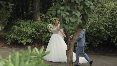 a bride and groom walk through a forest on their wedding day