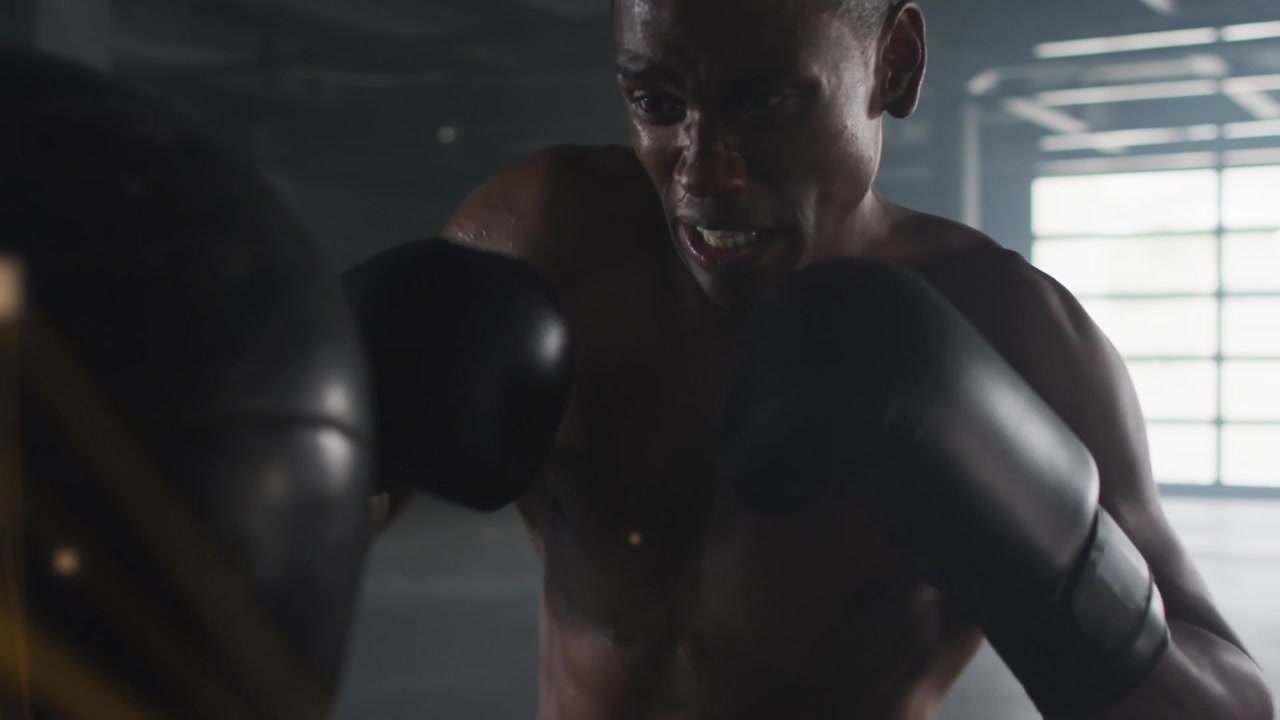 Boxer hitting heavy bag in industrial gym, strikes activating golden network overlay for power