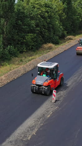 aerial view of asphalt rollers. road construction works with roller compactor machine vertical video