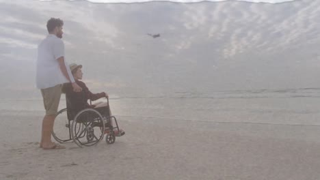 animation of sea over caucasian man with woman in wheelchair