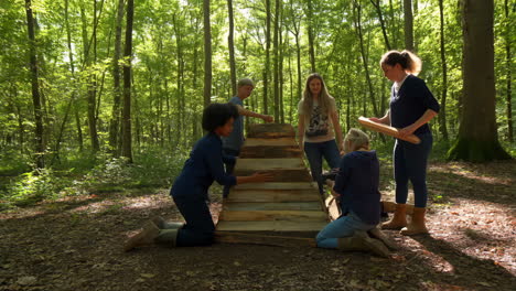 a group of people collaboratively building a wooden structure in a sunlit forest