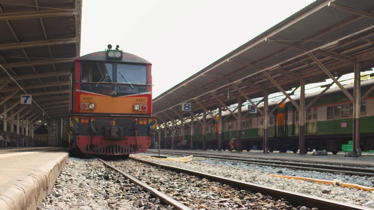 Inquadratura dal basso di un motore di un treno diesel rosso che arriva in una stazione ferroviaria storica