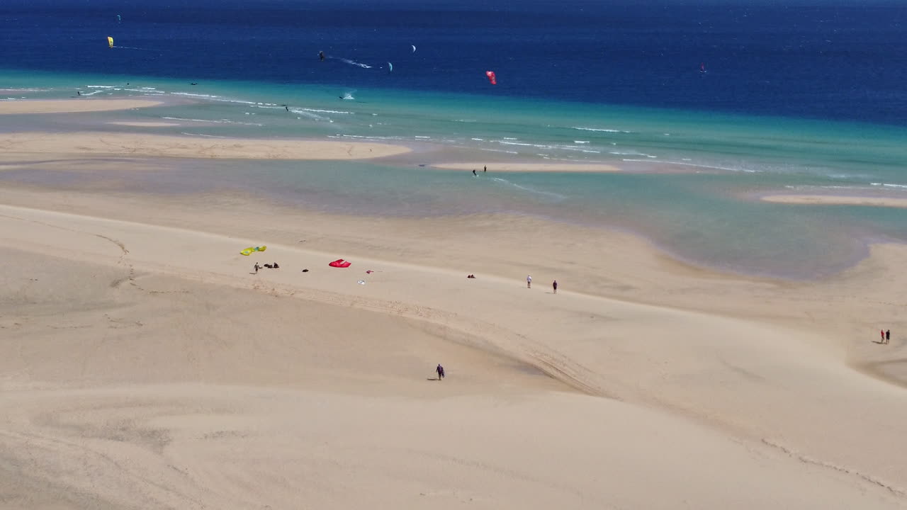 푸에르테벤투라 의 넓은 해변 과 푸른 물 에서 카이트보딩 을 하는 사람 들
