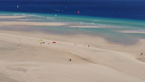 gente haciendo kiteboarding en la vasta playa y las aguas azules de fuerteventura