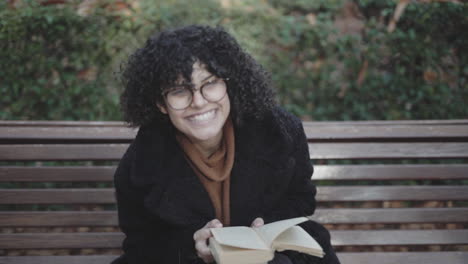 Nerdy-girl-with-curls-reading-a-book-posing-portrait-at-El-Retiro-Madrid-Spain