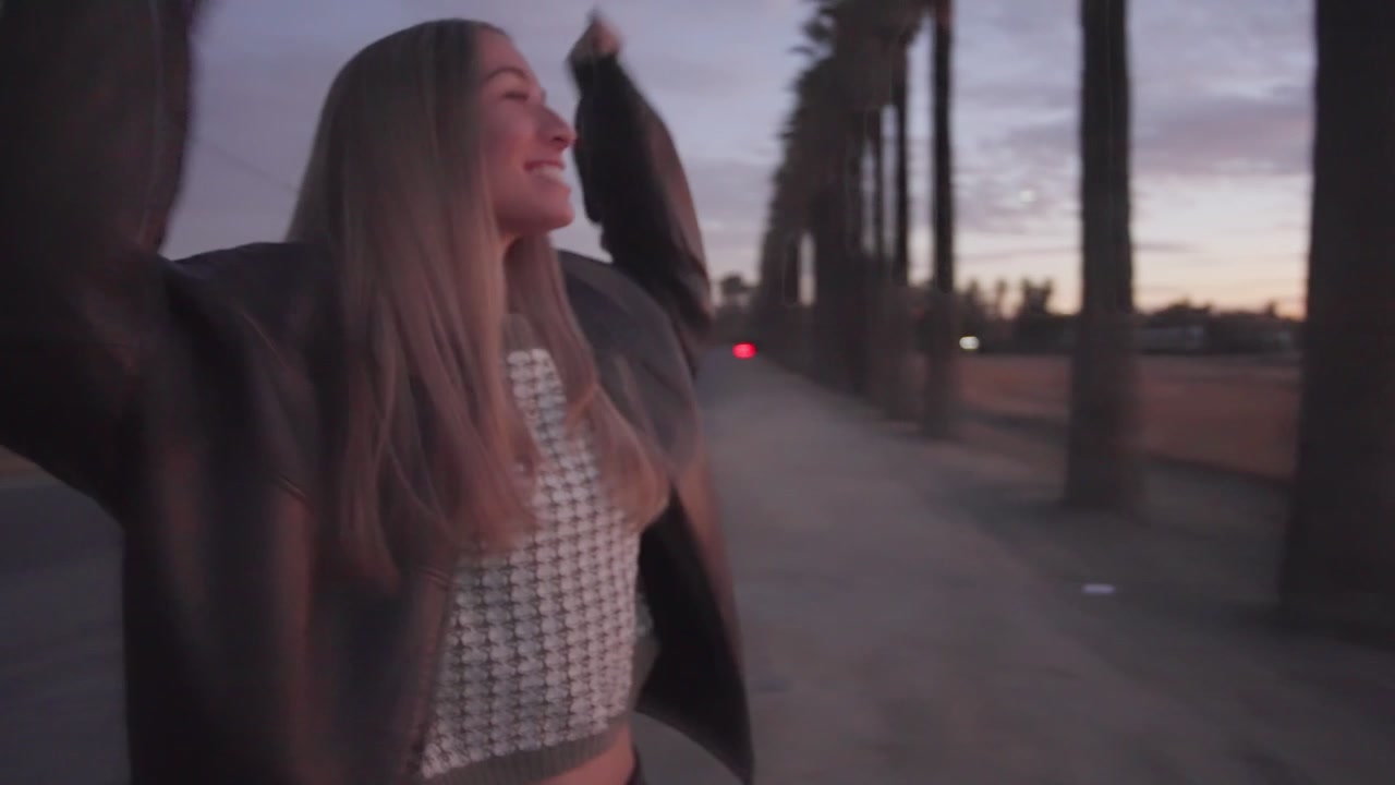 Modella giocosa che si sente meravigliosa e di successo al tramonto, palme nelle ore dorate