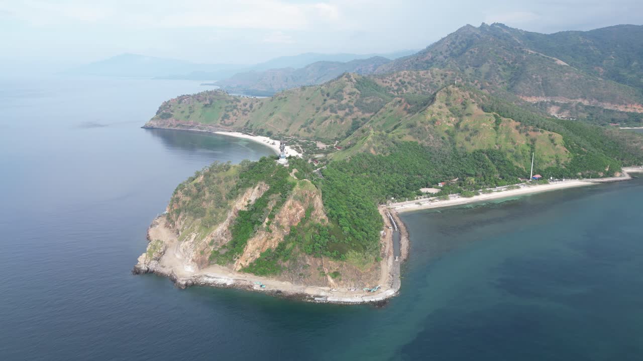 Sebuah semenanjung pesisir dengan bukit-bukit hijau dan air biru di Timor-Leste pada siang hari, tampilan udara.