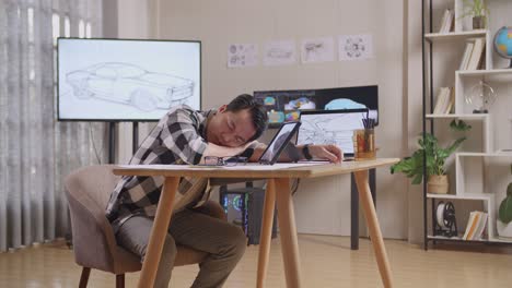 side view of asian male sleeping while drawing new car design concept on a tablet in the studio with tv and computers display 3d electric car model