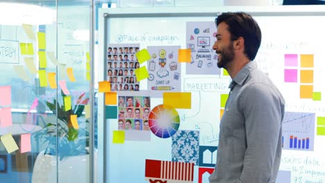ejecutivo masculino mirando notas adhesivas en la pizarra