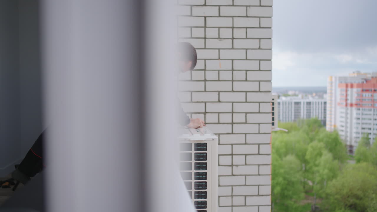 Fastening and installation of an external air conditioning unit on a high floor. Dangerous installation of air cooling systems.