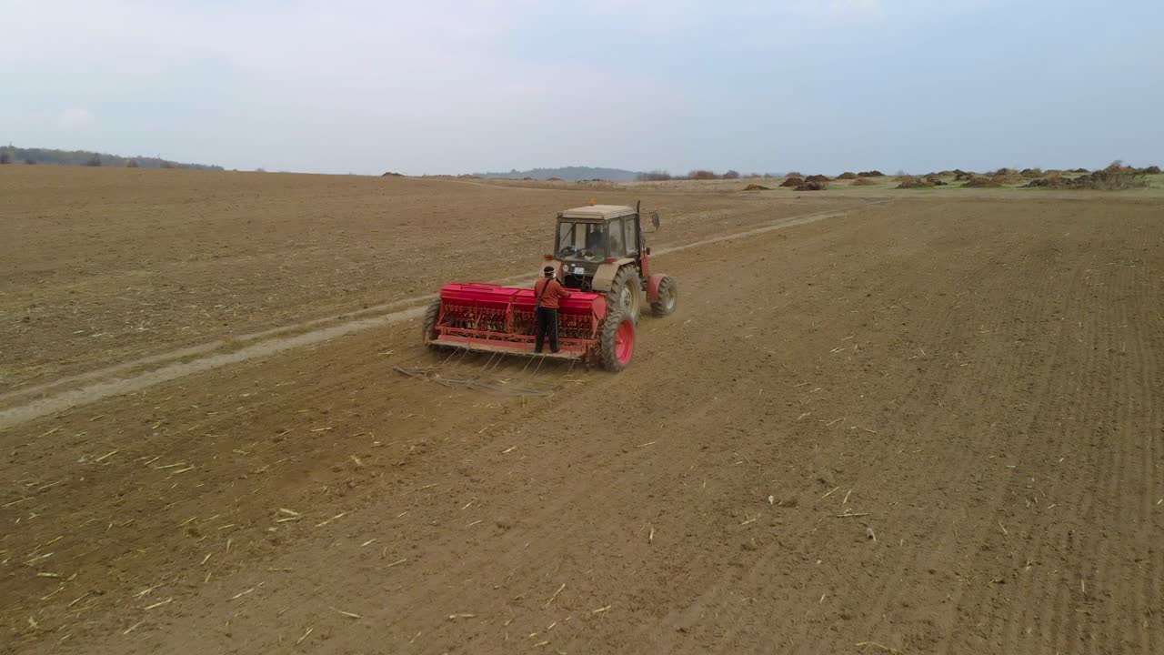 tractor, maquinaria agrícola y trabajadores siembran un campo - tiro de seguimiento aéreo
