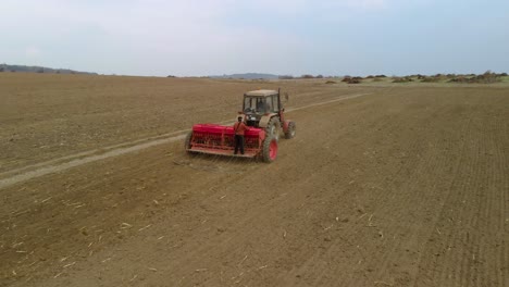 tractor, maquinaria agrícola y trabajadores siembran un campo - tiro de seguimiento aéreo
