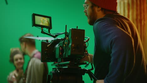 portrait of cameraman on railway trolley shooting green screne scene. professional crew on big budget filmmaking. on film studio set shooting historical movie green screen scene. slow motion arc shot