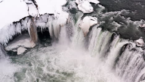 aerial top down shot of gigantic godafoss waterfall splashing and crashing during cold winter day,iceland