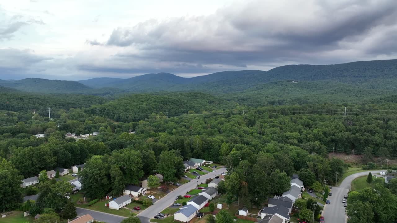 Fredeligt amerikansk nabolag med parcelhuse på grønne Blue Ridge Mountains. Virginia om sommeren med mørke skyer på himlen. Boliger i middelklassen i forstæderne. Luftfoto i bredformat
