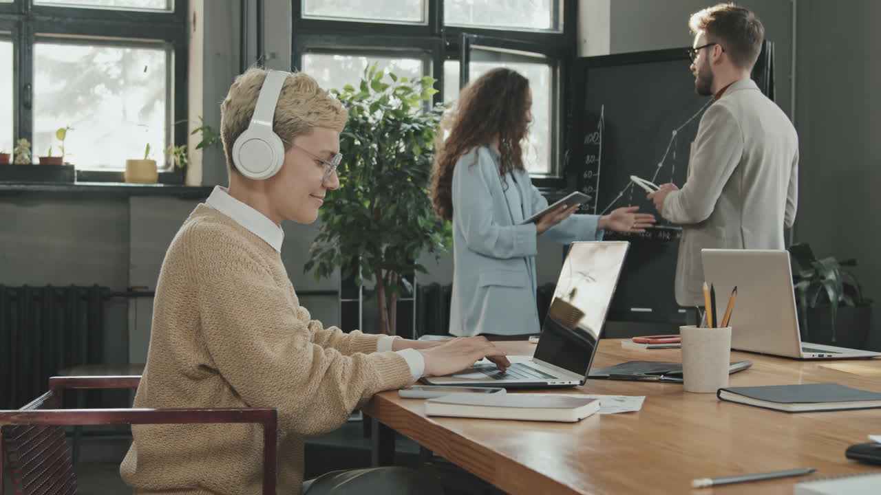 Donna moderna con cuffie che ascolta musica al lavoro