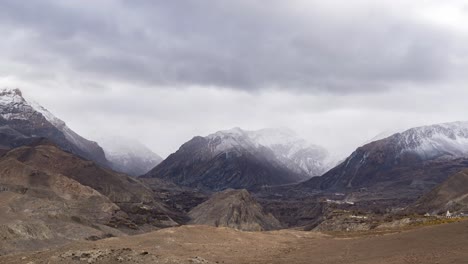 un video de lapso de tiempo de nubes moviéndose sobre las escarpadas montañas del himalaya con la ciudad de muktinath en el fondo