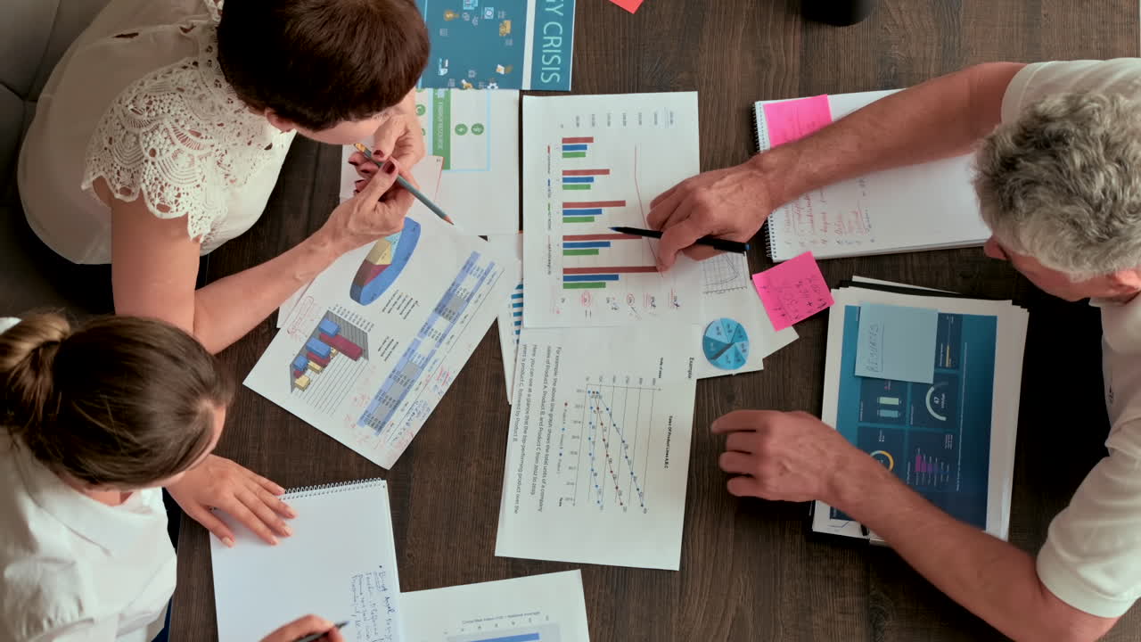 Three coworkers analysing graphs at a desk in an office