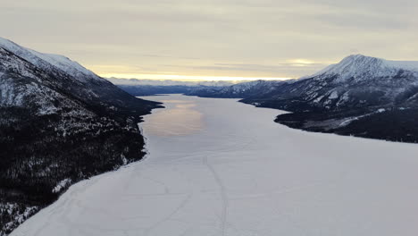frozen waters of kusawa lake on takhini river at sunset. winter in yukon territory, canada. wide drone shot