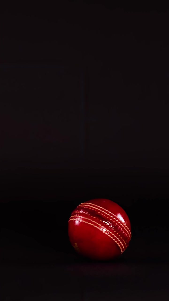 Röd cricketboll rör sig över mörk bakgrund