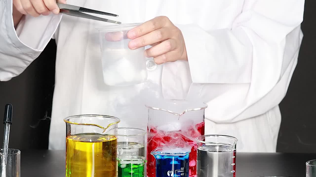 A scientist uses dry ice to create reactions with colorful liquids in beakers, producing smoke and bubbles.