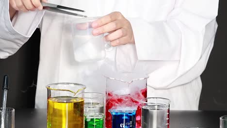 a scientist uses dry ice to create reactions with colorful liquids in beakers, producing smoke and bubbles.