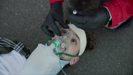 hombre, paramédico y manos con linterna en los ojos