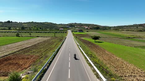 biker travelling on an empty village road riding a chopper