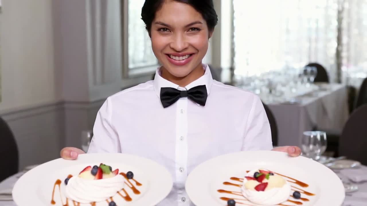 Pretty waitress showing dessert plates