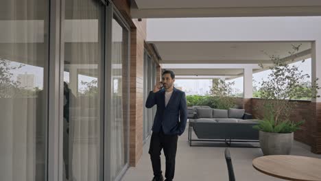 businessman confidently walking and talking on the phone, camera moves backwards, modern corporate office.