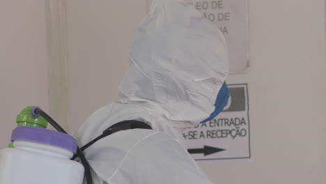 soldado con equipo de materiales peligrosos rocía las paredes del hospital con líquido desinfectante