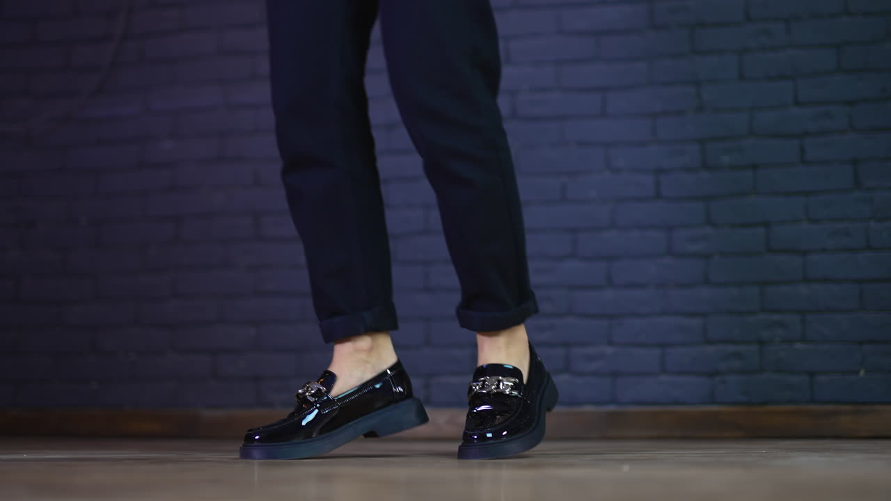 Black lacquered shoes with silver chain on massive soles demonstration. Female model rises on toes wearing fashionable shoes.