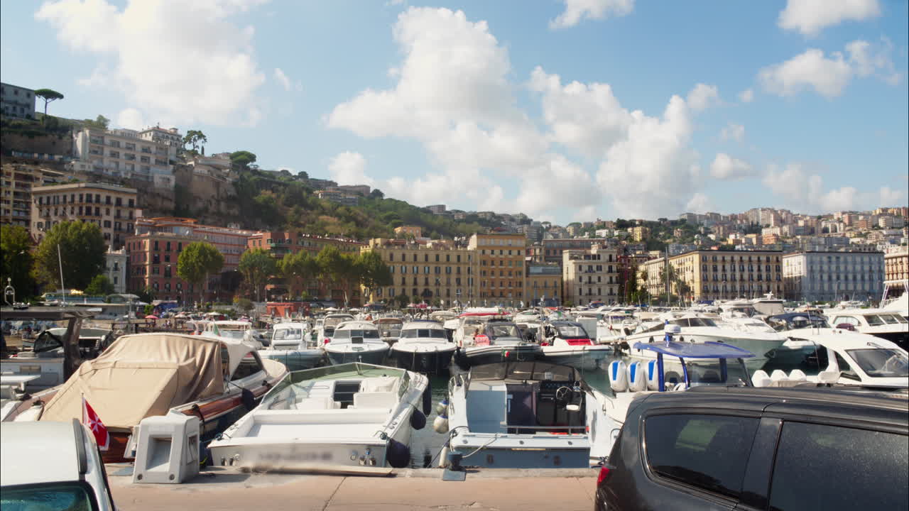 Giornata di sole alla Marina di Napoli con edifici cittadini e yacht.