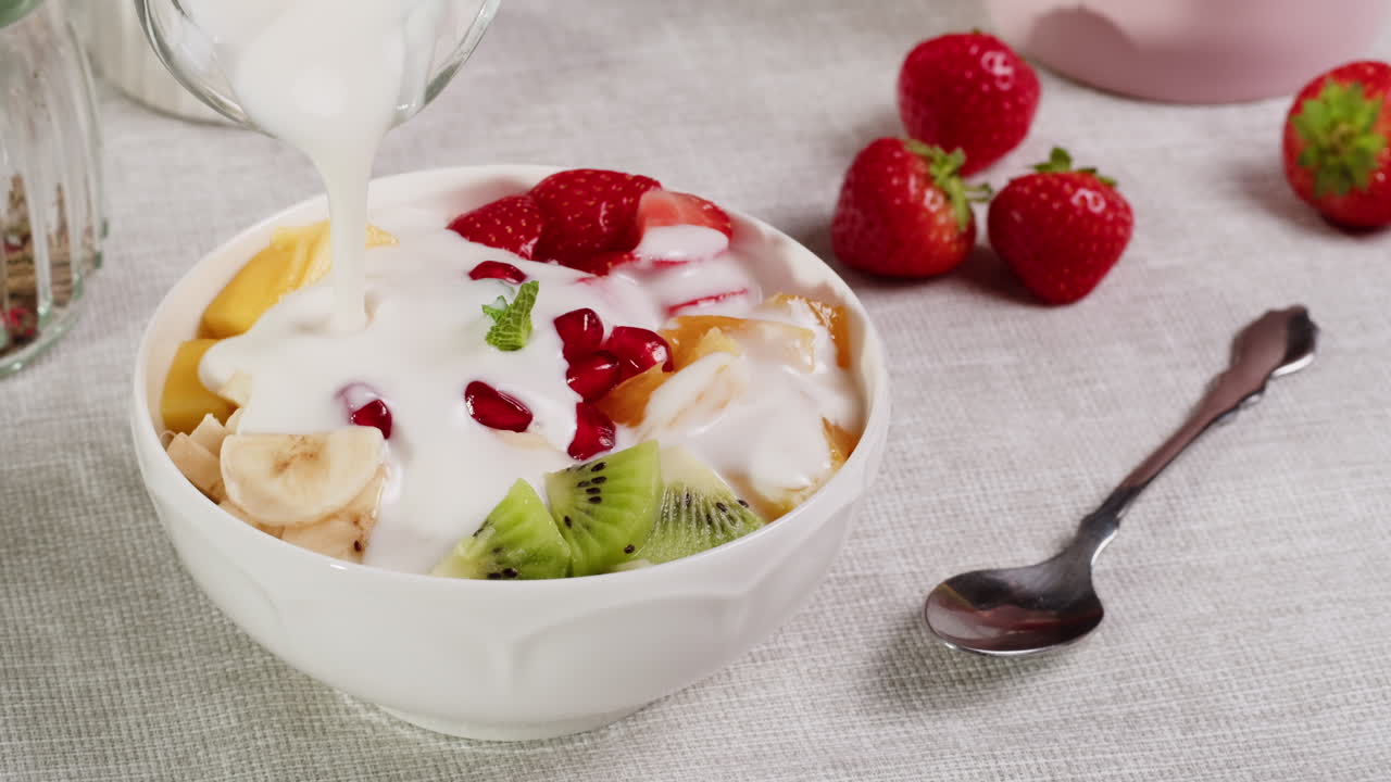 Despejando Iogurte Sobre uma Tigela de Frutas Frescas Mistas