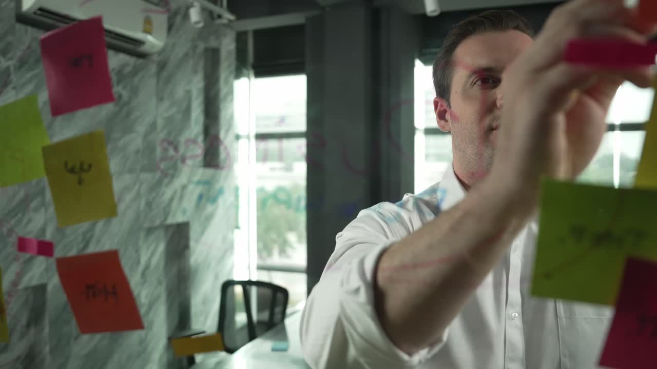 líder masculino profesional escribiendo una idea de marketing en notas adhesivas. manipulador.