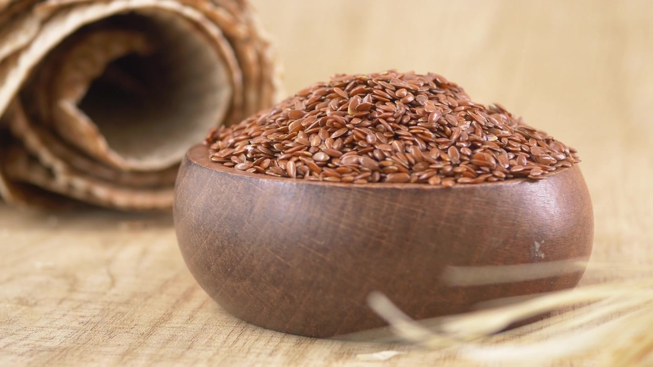 Wooden Bowl Filled with Organic Flax Seeds on Wooden Surface