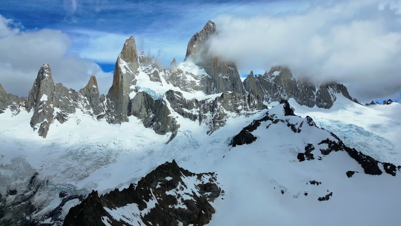 Vista aerea con drone delle spettacolari cime di granito del Fitz Roy parzialmente coperte da nuvole, con ghiacciai che si estendono sui pendii