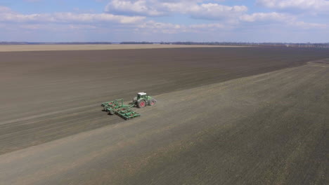 video de seguimiento aéreo: el tractor procesa el suelo en el campo se mueve a lo largo de la diagonal del marco 1