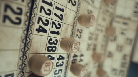 A-Vertical-Macro-video-of-a-Bingo-board,-studio-lights,-120-fps,-slow-motion,-wooden-chip-digits,-Raw-footage,-vintage-lottery-desk-game,-card-numbers,-crane-pull-back-smooth-movement