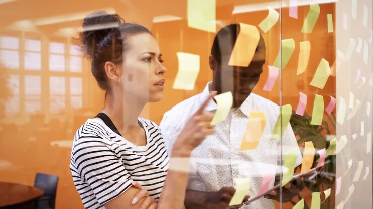 Male and female business executives discussing over digital tablet while reading sticky notes