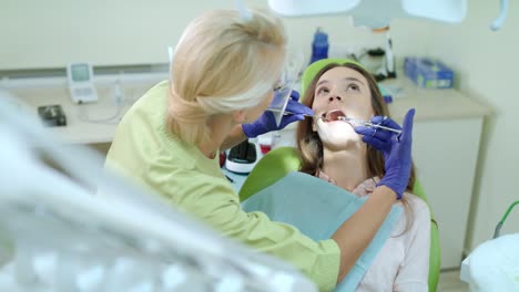 female dentist using mouth mirror and medicine syringe. doctor treating patient