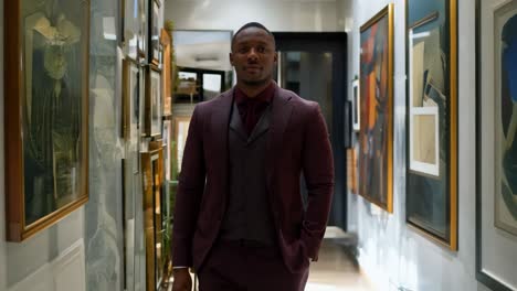 a man in a suit standing in a hallway with pictures on the wall