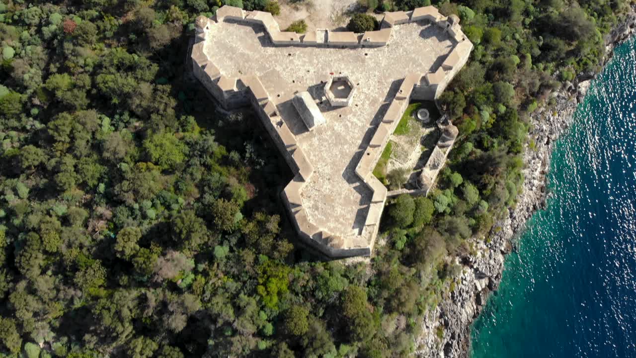 Fortezza medievale albanese a forma triangolare costruita su scogliere bagnate dal mare Mediterraneo blu turchese.