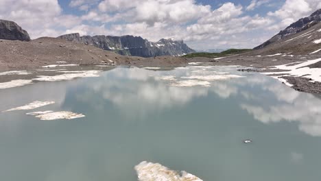 tranquilo lago alpino con manchas de nieve flotantes y montañas lejanas en klausenpass en suiza