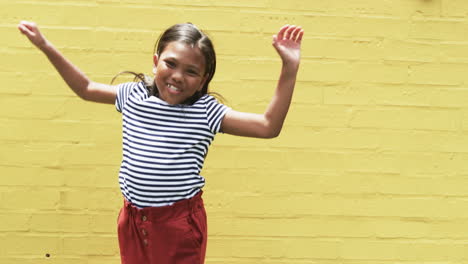 In-a-school-setting,-a-young-biracial-girl-smiles-against-a-yellow-background-with-copy-space