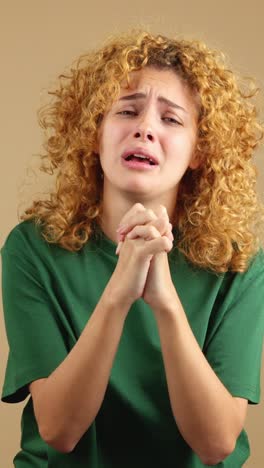 young woman crying or pleading with clasping hands